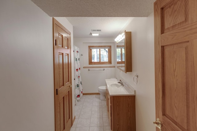 bathroom with toilet, vanity, a textured ceiling, and tile patterned flooring