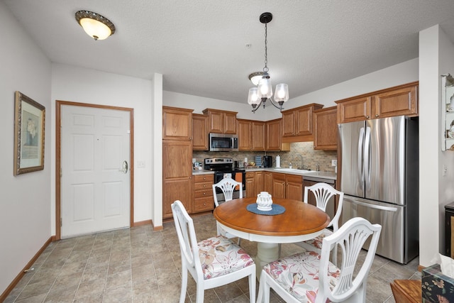 kitchen with decorative backsplash, appliances with stainless steel finishes, a textured ceiling, pendant lighting, and sink