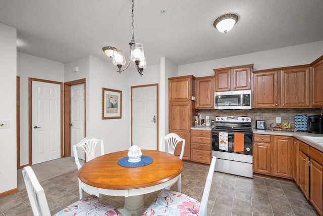 kitchen with tasteful backsplash, a textured ceiling, a chandelier, stainless steel appliances, and decorative light fixtures