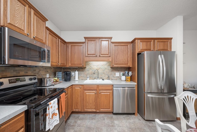 kitchen featuring appliances with stainless steel finishes, decorative backsplash, sink, and a textured ceiling