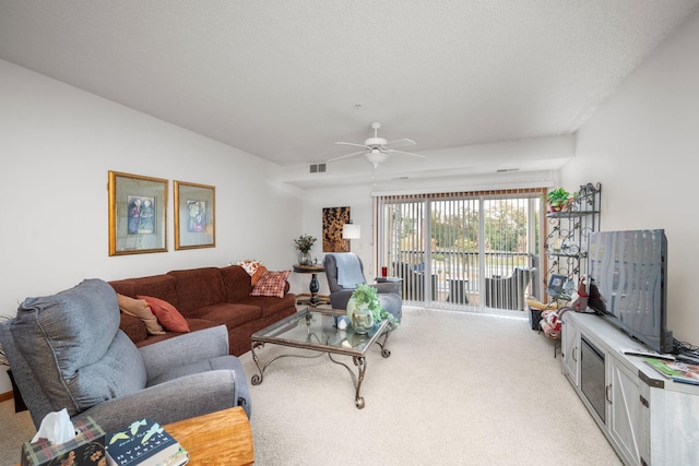 carpeted living room with a textured ceiling and ceiling fan