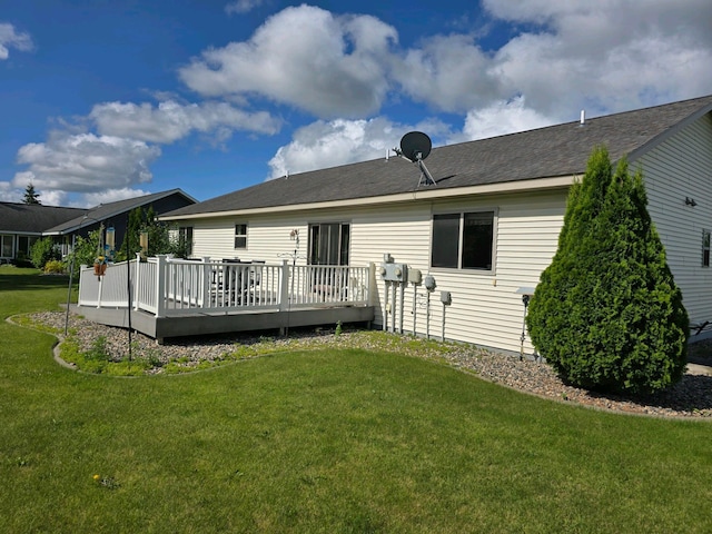 rear view of property featuring a deck and a lawn