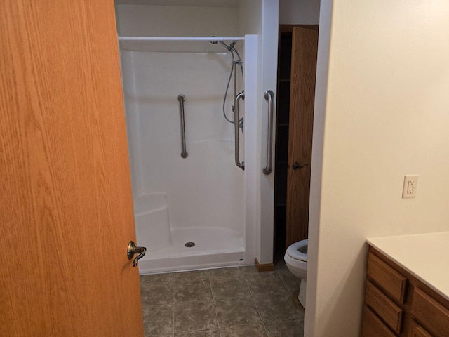 bathroom with vanity, a shower, toilet, and tile patterned floors