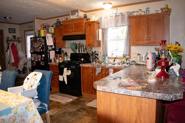 kitchen featuring a peninsula, a textured ceiling, brown cabinetry, under cabinet range hood, and black appliances