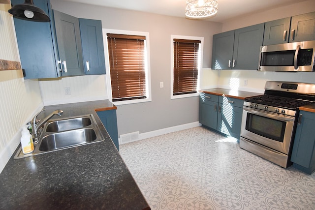 kitchen with blue cabinetry, stainless steel appliances, and sink