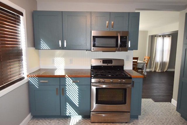 kitchen with wood counters, light wood-type flooring, stainless steel appliances, and blue cabinets