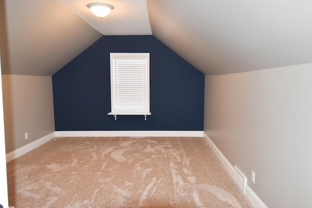 additional living space featuring light colored carpet and vaulted ceiling