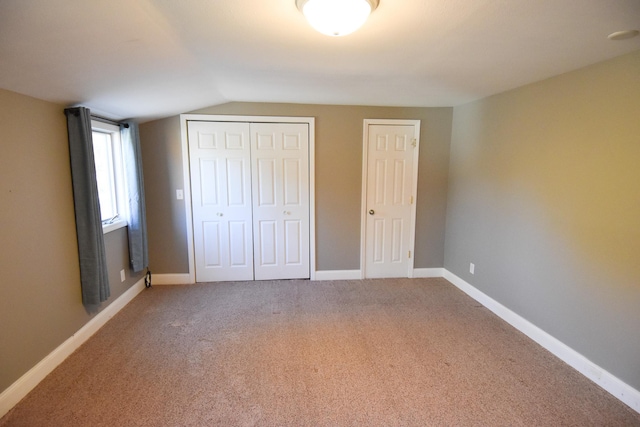 unfurnished bedroom featuring carpet flooring and vaulted ceiling