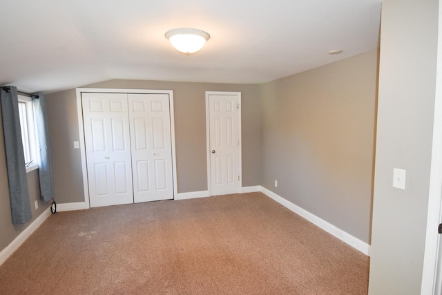 unfurnished bedroom featuring carpet flooring, multiple closets, and lofted ceiling