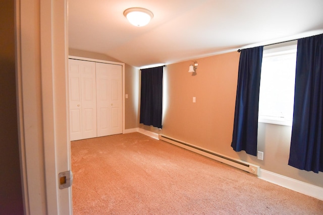 unfurnished bedroom with a closet, carpet, a baseboard radiator, and vaulted ceiling