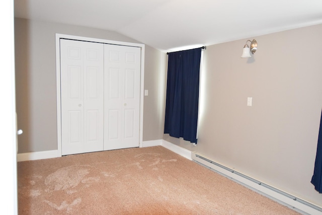 unfurnished bedroom with carpet floors, a baseboard radiator, a closet, and lofted ceiling