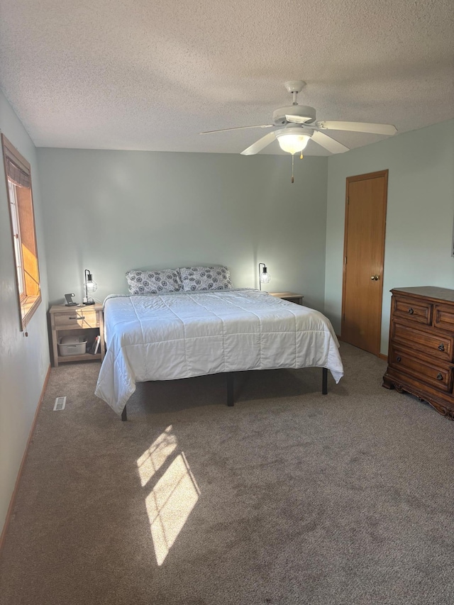 carpeted bedroom with ceiling fan and a textured ceiling