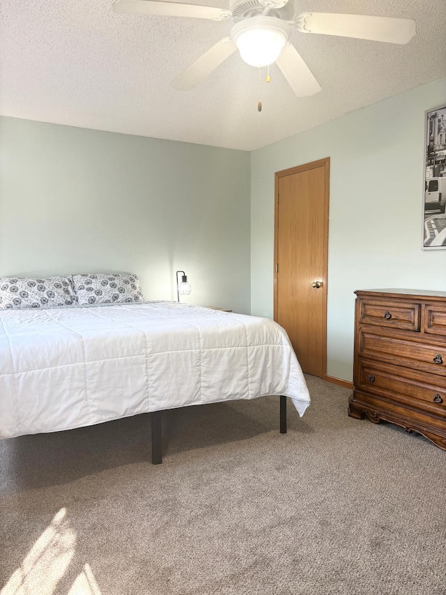 carpeted bedroom featuring ceiling fan and a textured ceiling