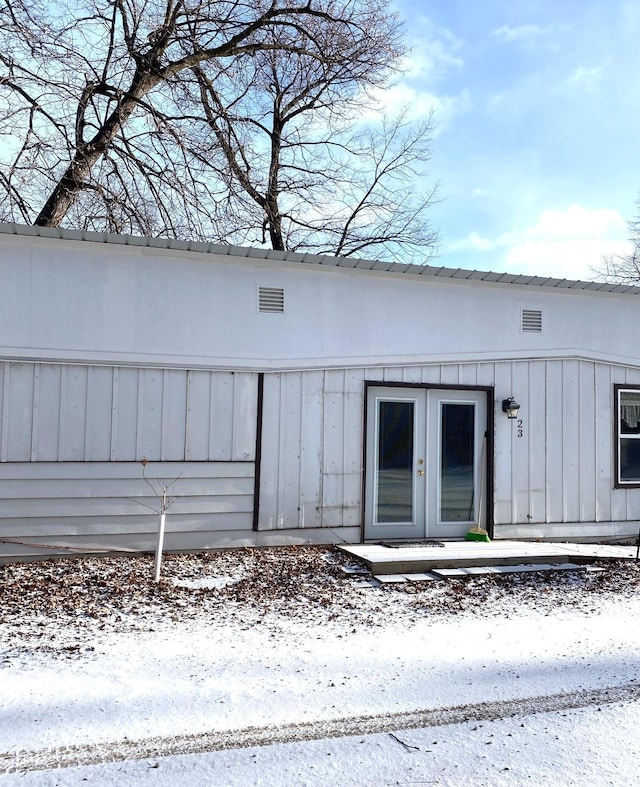 snow covered property entrance featuring french doors