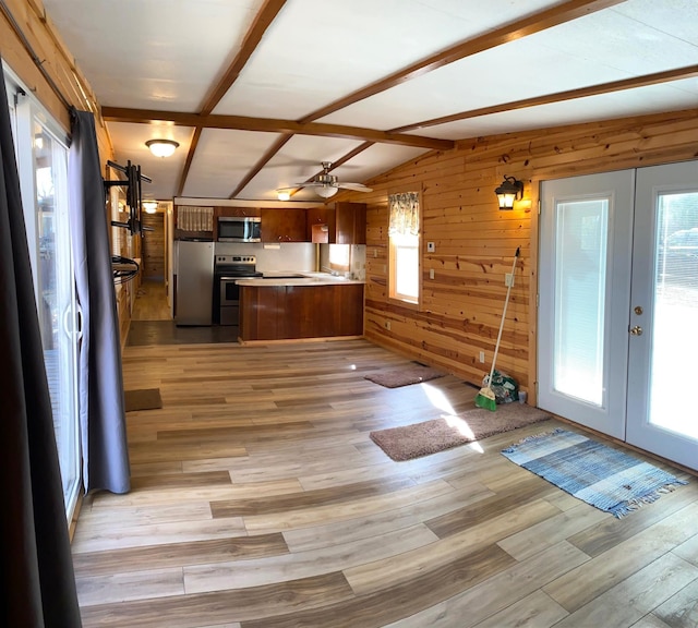 kitchen with french doors, lofted ceiling with beams, wooden walls, light wood-type flooring, and appliances with stainless steel finishes