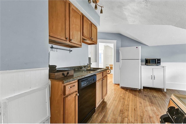 kitchen featuring dishwasher, sink, vaulted ceiling, white refrigerator, and a textured ceiling