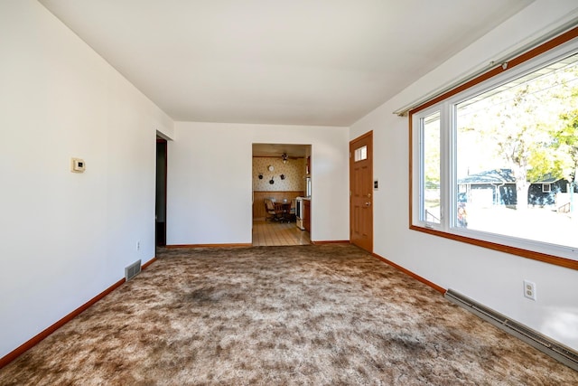 unfurnished living room with baseboard heating and carpet floors