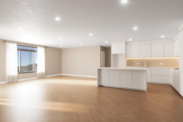 kitchen featuring light parquet floors, white cabinetry, and sink