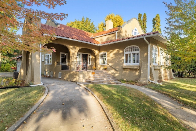 mediterranean / spanish home with a porch and a front lawn