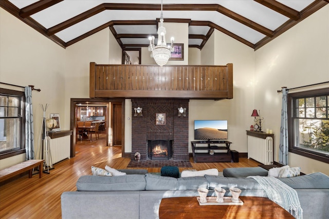 living room featuring high vaulted ceiling, a notable chandelier, light hardwood / wood-style flooring, and a fireplace