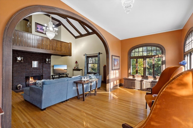 living room with light wood-type flooring, a fireplace, beam ceiling, high vaulted ceiling, and an inviting chandelier