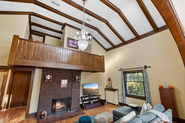 living room with high vaulted ceiling, a brick fireplace, light wood-type flooring, and radiator heating unit