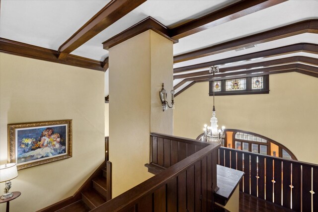 stairway with beam ceiling, a wealth of natural light, and a chandelier