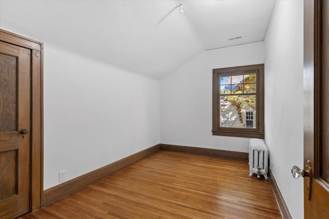 additional living space with light hardwood / wood-style flooring, radiator heating unit, and lofted ceiling