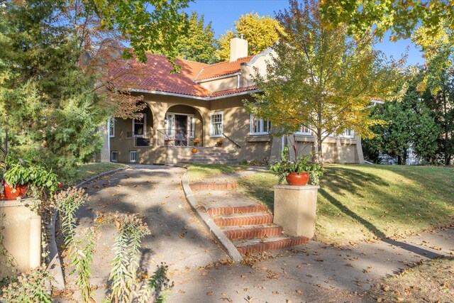 mediterranean / spanish home with a front lawn and a porch