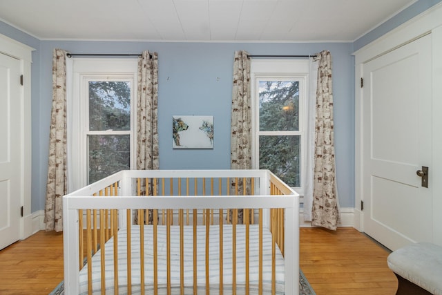 bedroom featuring ornamental molding, hardwood / wood-style flooring, and a crib