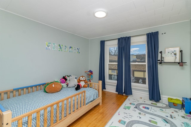 bedroom with crown molding and wood-type flooring