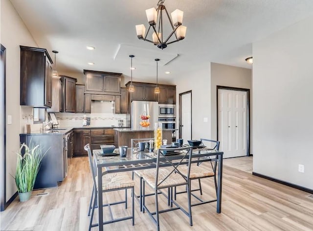 dining space featuring light hardwood / wood-style floors, sink, and a chandelier