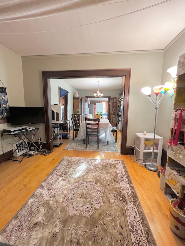 living room with wood-type flooring, ornamental molding, and a chandelier