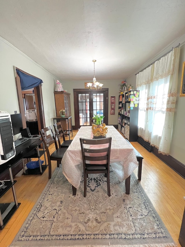 dining space with french doors, light hardwood / wood-style flooring, and a chandelier