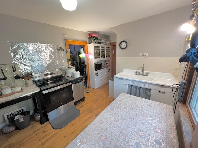 kitchen featuring white cabinetry, sink, light wood-type flooring, and stainless steel electric range oven