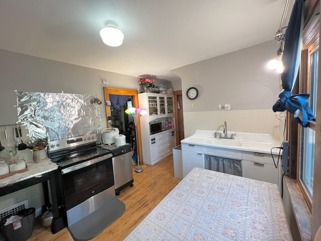 kitchen featuring stainless steel electric stove, white cabinetry, and light wood-type flooring