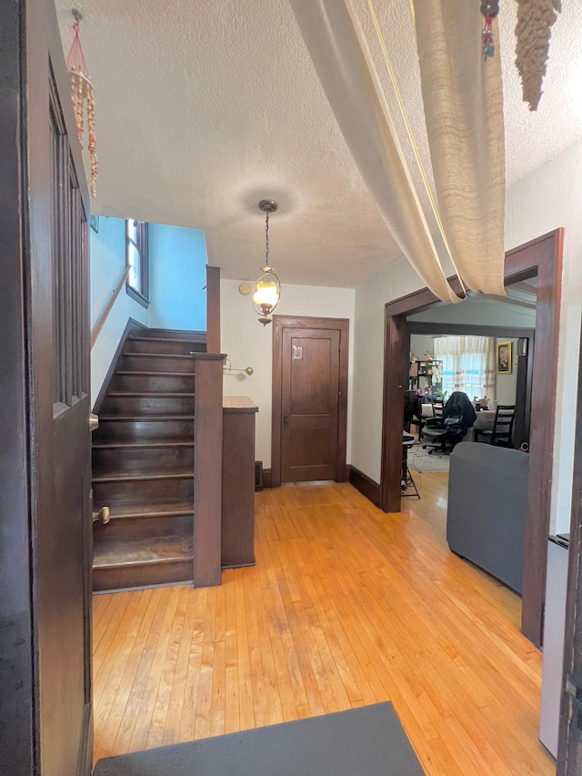 staircase featuring beamed ceiling, hardwood / wood-style floors, and a textured ceiling