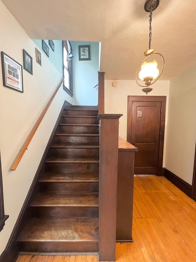 stairway featuring a textured ceiling and hardwood / wood-style flooring