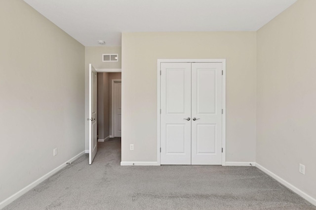 unfurnished bedroom featuring carpet floors, a closet, visible vents, and baseboards