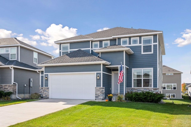 view of front of home featuring roof with shingles, a front yard, a garage, stone siding, and driveway