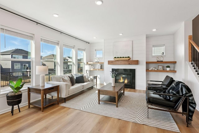 living room featuring baseboards, a glass covered fireplace, wood finished floors, and recessed lighting