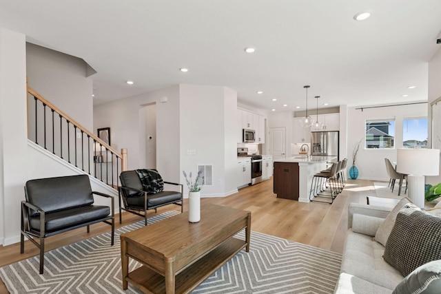 living area featuring light wood finished floors, stairway, visible vents, and recessed lighting