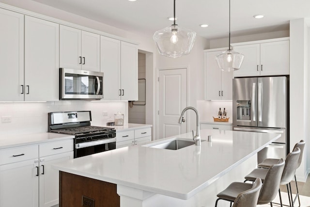 kitchen featuring a breakfast bar, stainless steel appliances, backsplash, a kitchen island with sink, and a sink