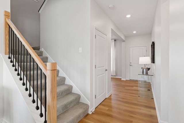 stairs featuring baseboards, wood finished floors, and recessed lighting