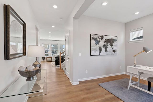 hallway featuring stairs, recessed lighting, light wood-style flooring, and baseboards