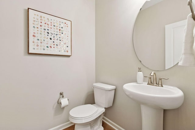 bathroom featuring wood finished floors, a sink, toilet, and baseboards