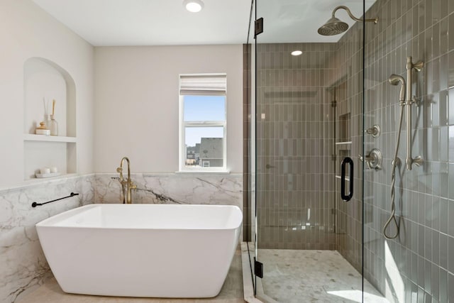 full bathroom with tile walls, a wainscoted wall, a freestanding bath, and a shower stall