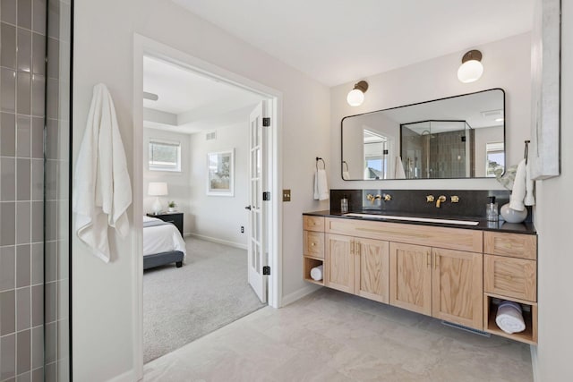 ensuite bathroom with baseboards, ensuite bathroom, tiled shower, and vanity