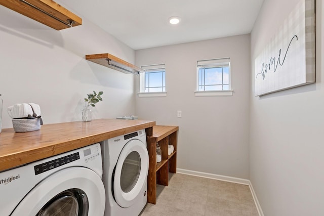 washroom featuring laundry area, separate washer and dryer, and baseboards