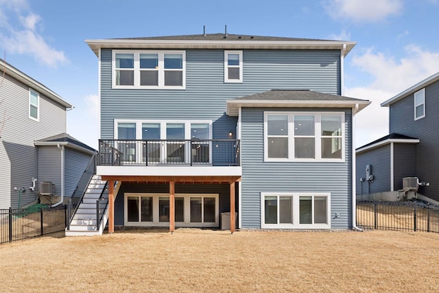 back of property with a deck, a yard, fence, and stairway